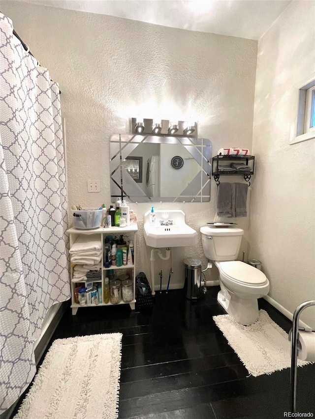 bathroom featuring a sink, a textured wall, a shower with curtain, wood-type flooring, and toilet