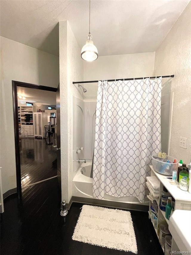 full bath featuring a textured wall, shower / bath combo, wood finished floors, and baseboards