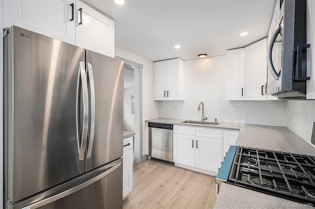 kitchen with sink, tasteful backsplash, light hardwood / wood-style flooring, appliances with stainless steel finishes, and white cabinets