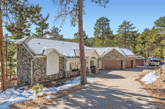 view of front facade featuring a garage, stone siding, and decorative driveway