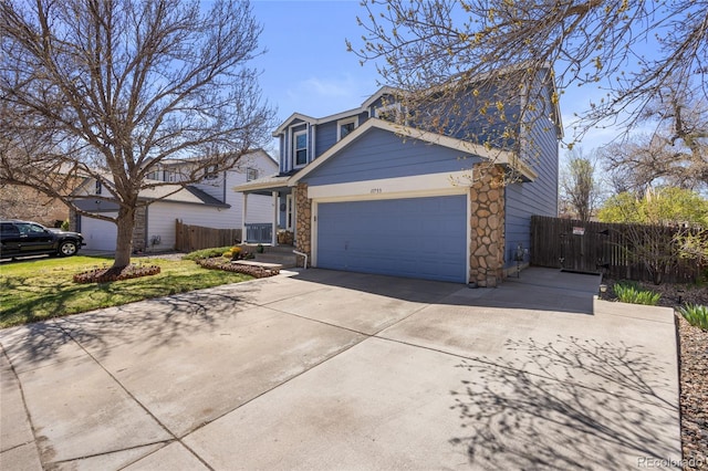 traditional-style home featuring fence, a garage, driveway, and stone siding