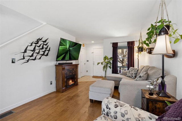 living area with light wood-type flooring, baseboards, recessed lighting, and a glass covered fireplace