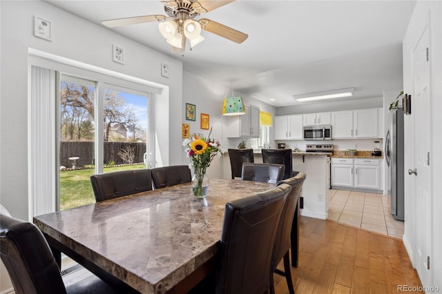dining space with light wood-style floors and ceiling fan