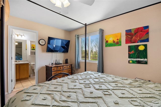 bedroom with ensuite bath, light tile patterned floors, a sink, and ceiling fan