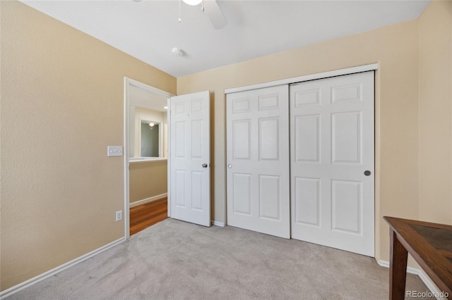 unfurnished bedroom featuring carpet, baseboards, a closet, and a ceiling fan
