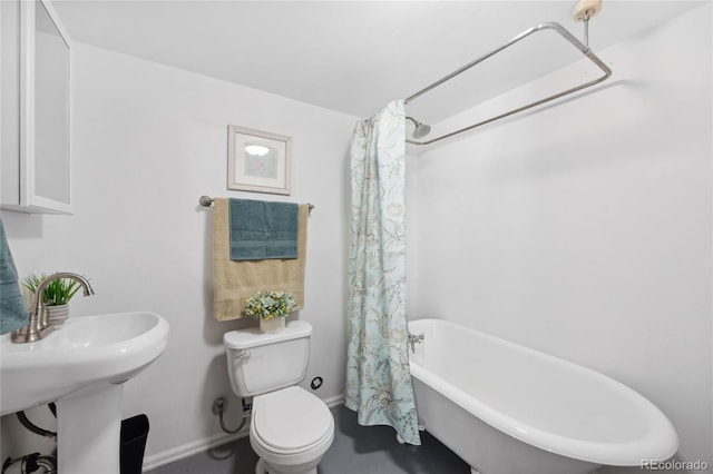 full bath featuring a freestanding bath, baseboards, a sink, toilet, and a shower with shower curtain