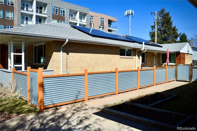 2200 S Cherry St Unit 2216, Denver, CO 80222 - view of side of property featuring roof mounted solar panels, brick siding, roof with shingles, and a porch