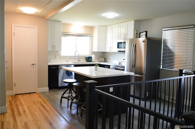 2200 S Cherry St Unit 2216, Denver, CO 80222 - kitchen with stainless steel appliances, a sink, a breakfast bar area, white cabinets, and light countertops