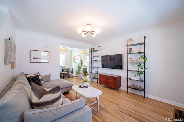 living room featuring light wood-type flooring, a chandelier, and crown molding