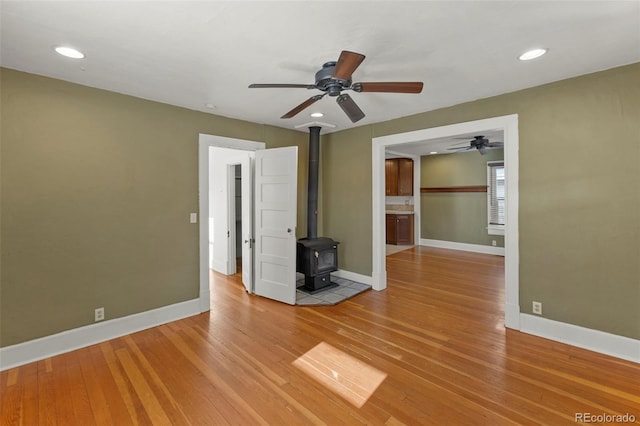 702 E Platte Ave, Colorado Springs, CO 80903 - empty room featuring a wood stove, ceiling fan, baseboards, light wood-style flooring, and recessed lighting