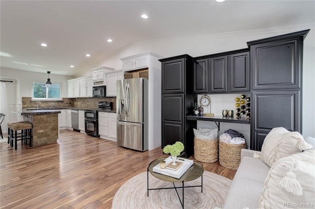 living room featuring light hardwood / wood-style floors, crown molding, and vaulted ceiling