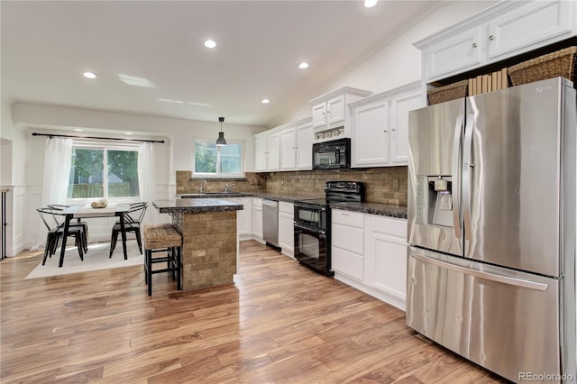 kitchen with light hardwood / wood-style flooring, black appliances, vaulted ceiling, and white cabinets