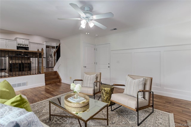 living room featuring ceiling fan, ornamental molding, and dark hardwood / wood-style floors