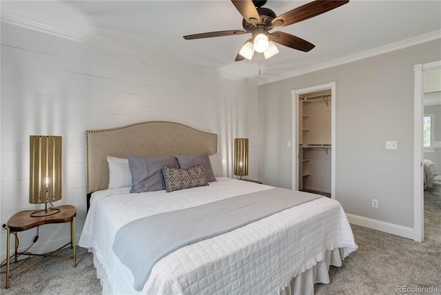 carpeted bedroom with a closet, ceiling fan, crown molding, and a walk in closet