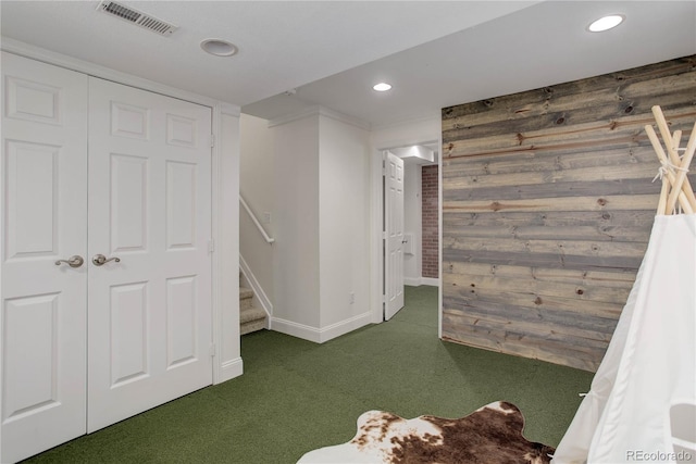 interior space with a closet, wood walls, and dark carpet