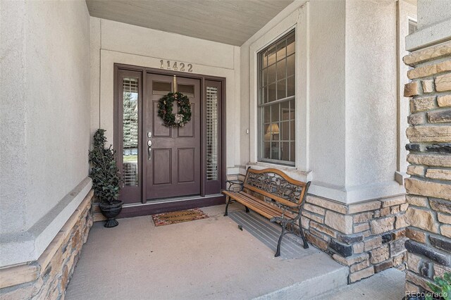 11422 W Cooper Ave, Littleton, CO 80127 - doorway to property featuring a porch and stucco siding