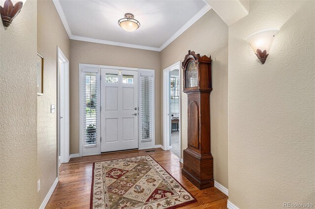 11422 W Cooper Ave, Littleton, CO 80127 - entrance foyer with a textured wall, crown molding, wood finished floors, baseboards, and arched walkways