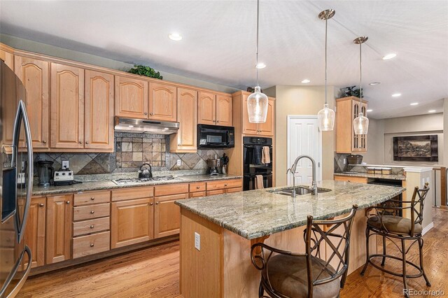 11422 W Cooper Ave, Littleton, CO 80127 - kitchen with a sink, black appliances, a breakfast bar, light wood finished floors, and under cabinet range hood