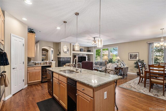 11422 W Cooper Ave, Littleton, CO 80127 - kitchen featuring a sink, a fireplace, arched walkways, dark wood-style floors, and an island with sink