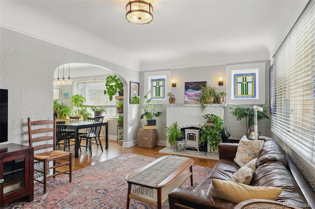 living room featuring a textured wall, baseboards, arched walkways, and wood finished floors