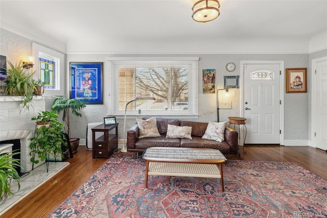 living area featuring a textured wall, baseboards, and wood finished floors