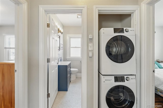 clothes washing area featuring stacked washer and dryer, laundry area, and a sink
