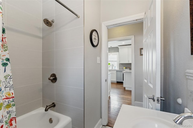 bathroom with wood finished floors, shower / bath combo with shower curtain, and a sink