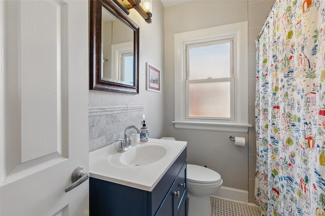 bathroom with toilet, curtained shower, vanity, and baseboards