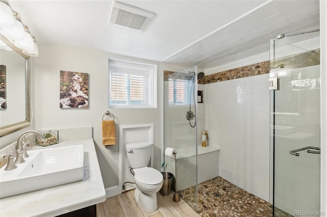 full bath with a shower stall, visible vents, toilet, and wood finished floors