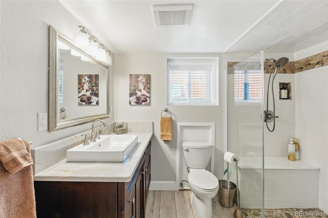full bath with toilet, a stall shower, wood finished floors, and visible vents