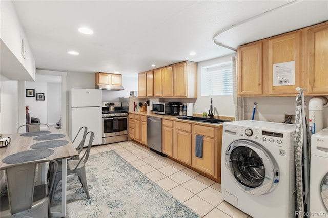 kitchen with stainless steel appliances, light tile patterned floors, washer and clothes dryer, and a sink