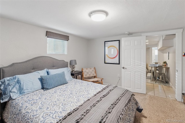 carpeted bedroom featuring a textured ceiling, baseboards, and tile patterned floors