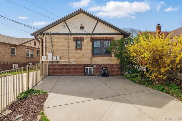 rear view of property with brick siding, stucco siding, and fence