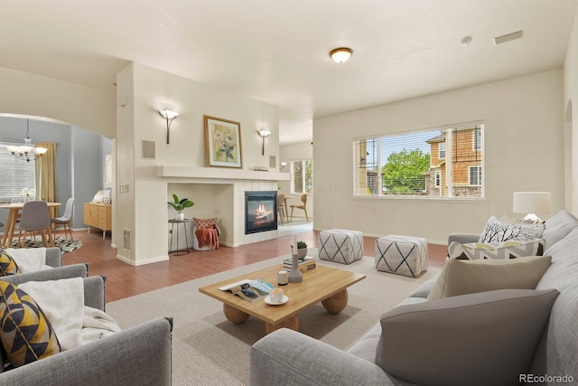297 N Coolidge Way, Aurora, CO 80018 - living room featuring wood finished floors, arched walkways, a chandelier, a tile fireplace, and baseboards