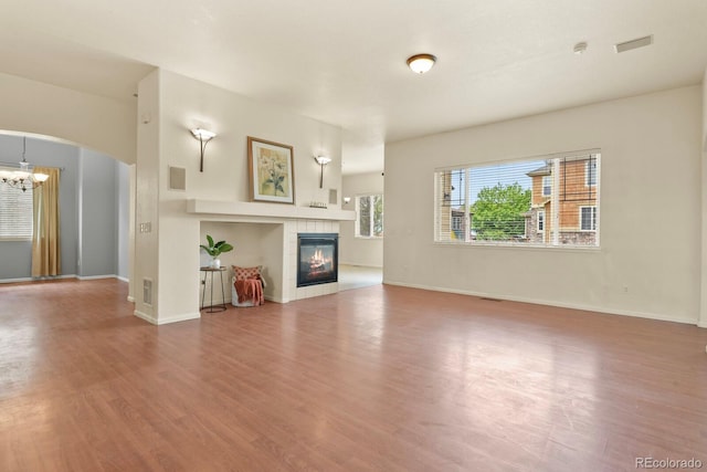 297 N Coolidge Way, Aurora, CO 80018 - unfurnished living room with arched walkways, wood finished floors, a chandelier, a fireplace, and baseboards
