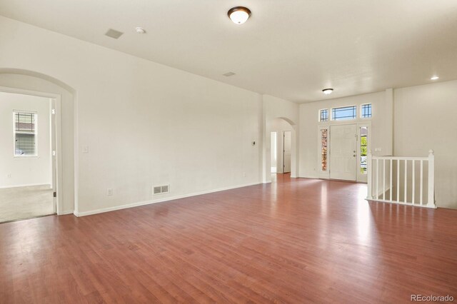 297 N Coolidge Way, Aurora, CO 80018 - unfurnished living room featuring arched walkways, wood finished floors, and baseboards