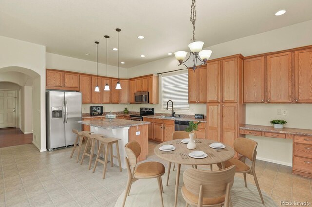 297 N Coolidge Way, Aurora, CO 80018 - kitchen featuring stainless steel appliances, a sink, a center island, arched walkways, and a chandelier
