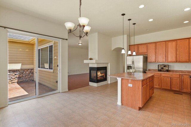 297 N Coolidge Way, Aurora, CO 80018 - kitchen featuring stainless steel fridge with ice dispenser, a kitchen island, pendant lighting, a multi sided fireplace, and recessed lighting