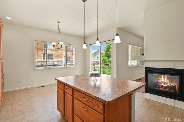 297 N Coolidge Way, Aurora, CO 80018 - kitchen featuring a center island, a fireplace, brown cabinetry, a chandelier, and decorative light fixtures