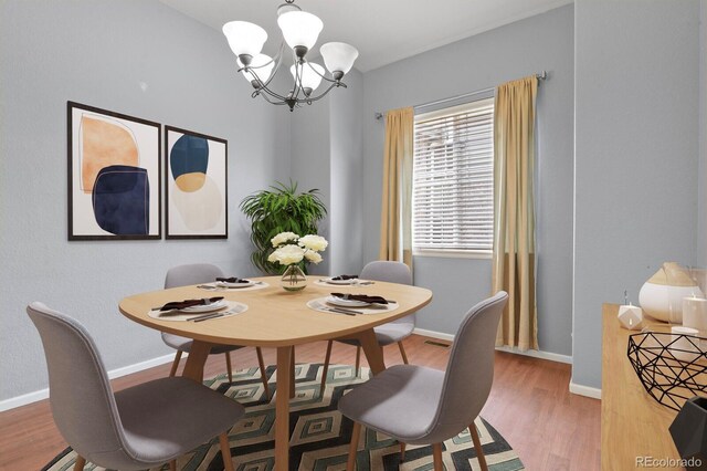 297 N Coolidge Way, Aurora, CO 80018 - dining area featuring a chandelier, wood finished floors, and baseboards