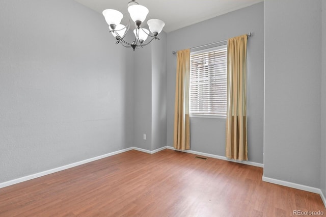297 N Coolidge Way, Aurora, CO 80018 - spare room featuring a chandelier, wood finished floors, and baseboards
