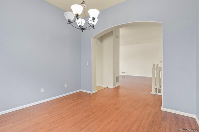 297 N Coolidge Way, Aurora, CO 80018 - spare room with arched walkways, a chandelier, light wood-style flooring, and baseboards