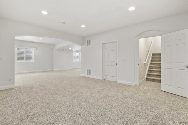 297 N Coolidge Way, Aurora, CO 80018 - spare room with arched walkways, light carpet, recessed lighting, stairs, and baseboards