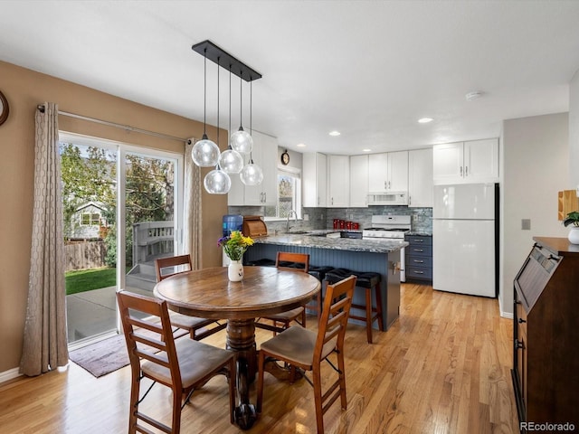 dining room featuring light wood-style flooring, baseboards, and recessed lighting