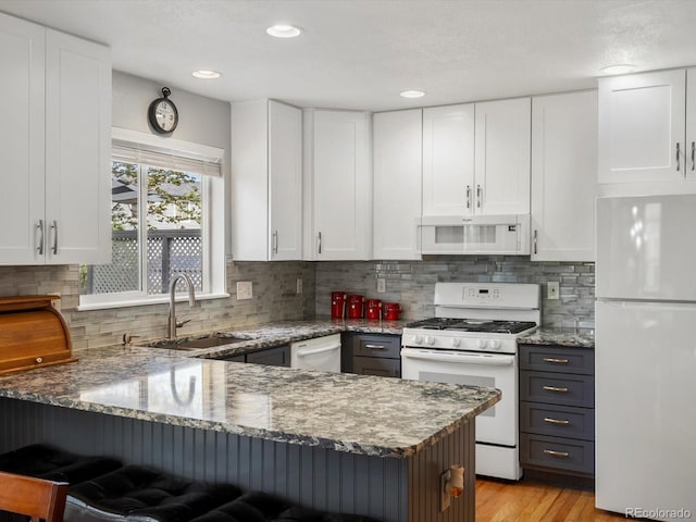 kitchen with white appliances, a sink, white cabinets, and recessed lighting