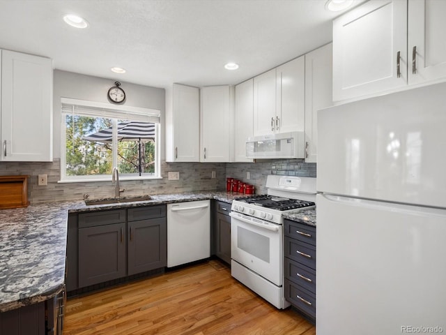 kitchen featuring white appliances, a sink, white cabinets, and recessed lighting