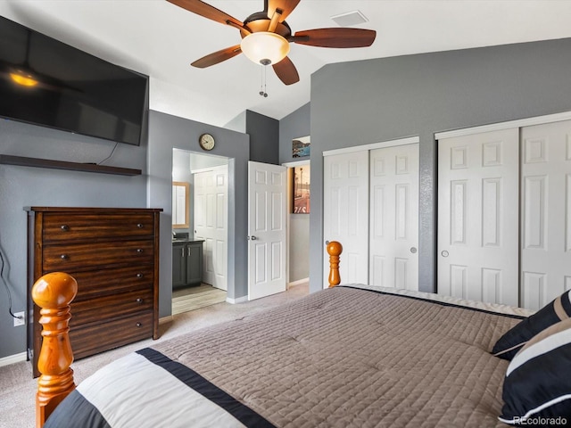 bedroom featuring vaulted ceiling, light colored carpet, two closets, baseboards, and ceiling fan