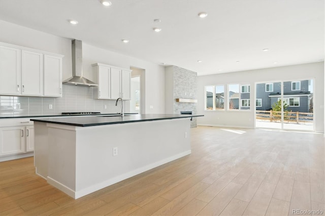 kitchen featuring wall chimney exhaust hood, sink, decorative backsplash, and white cabinets