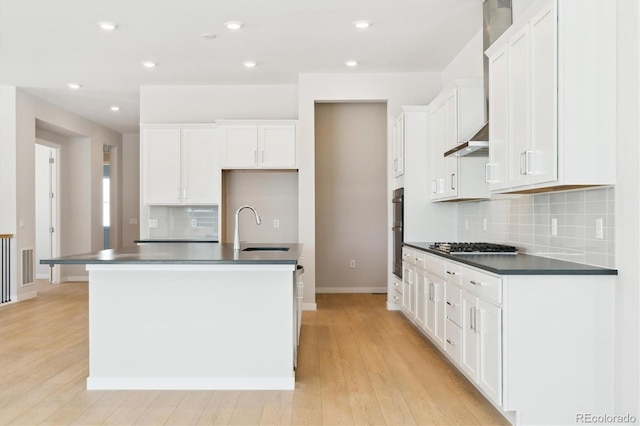 kitchen with light hardwood / wood-style floors, sink, a center island with sink, and white cabinets