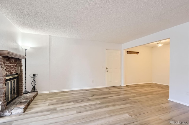 unfurnished living room featuring a fireplace, a textured ceiling, and light hardwood / wood-style flooring